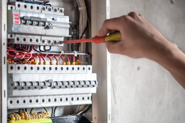 man-an-electrical-technician-working-in-a-switchboard-with-fuses-installation-and-connection-of-electrical-equipment-close-up-min-600x400